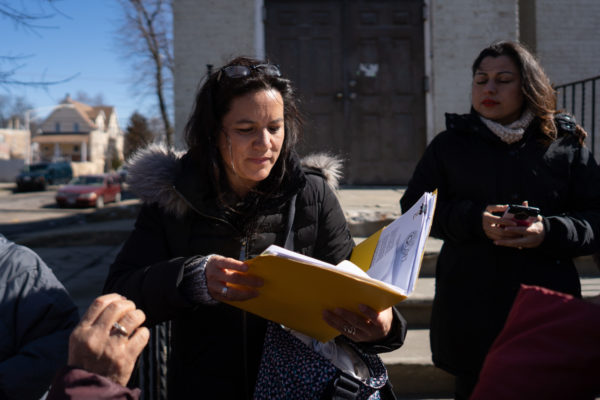 Una mujer lee algo en una carpeta mientras acompaña a un equipo de divulgación.