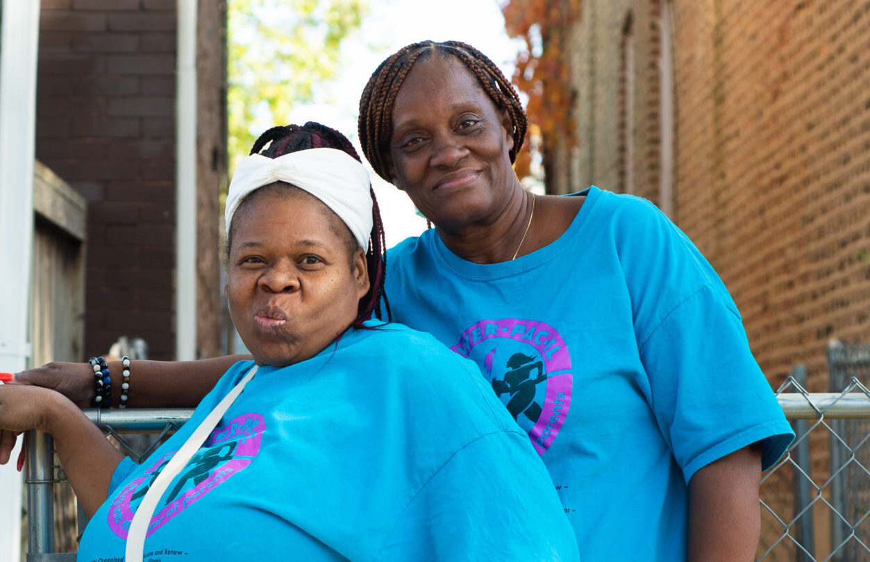 Two women in matching blue POWER-PAC IL shirts pose for a photo