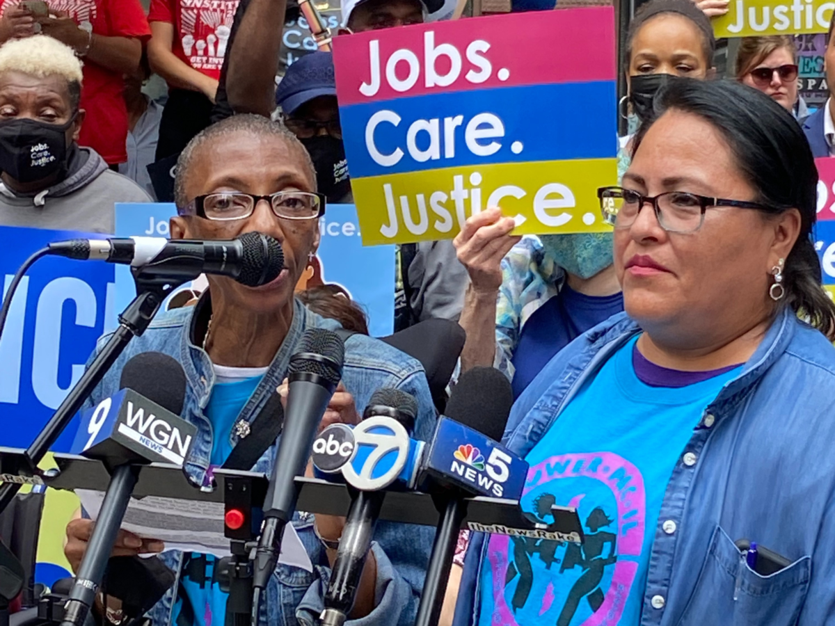 Una mujer afroamericana y una mujer latina con camisetas azules POWER-PAC IL hablan durante una conferencia de prensa