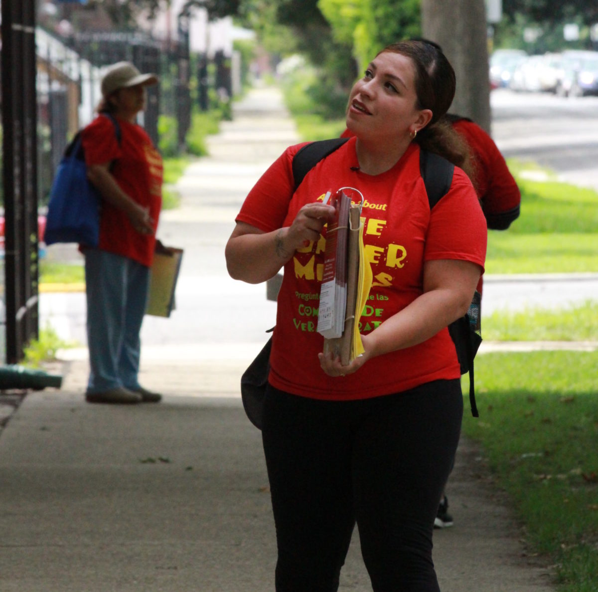 A woman wearing a bright red shirt conducts outreach for free summer meals