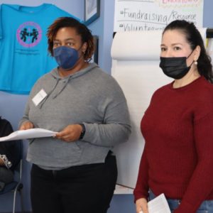 Two women in masks are facilitating a training session