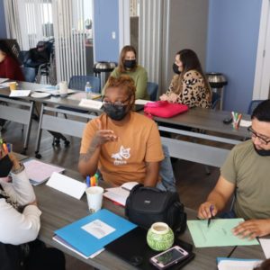 Three people are sitting a table having a discussion