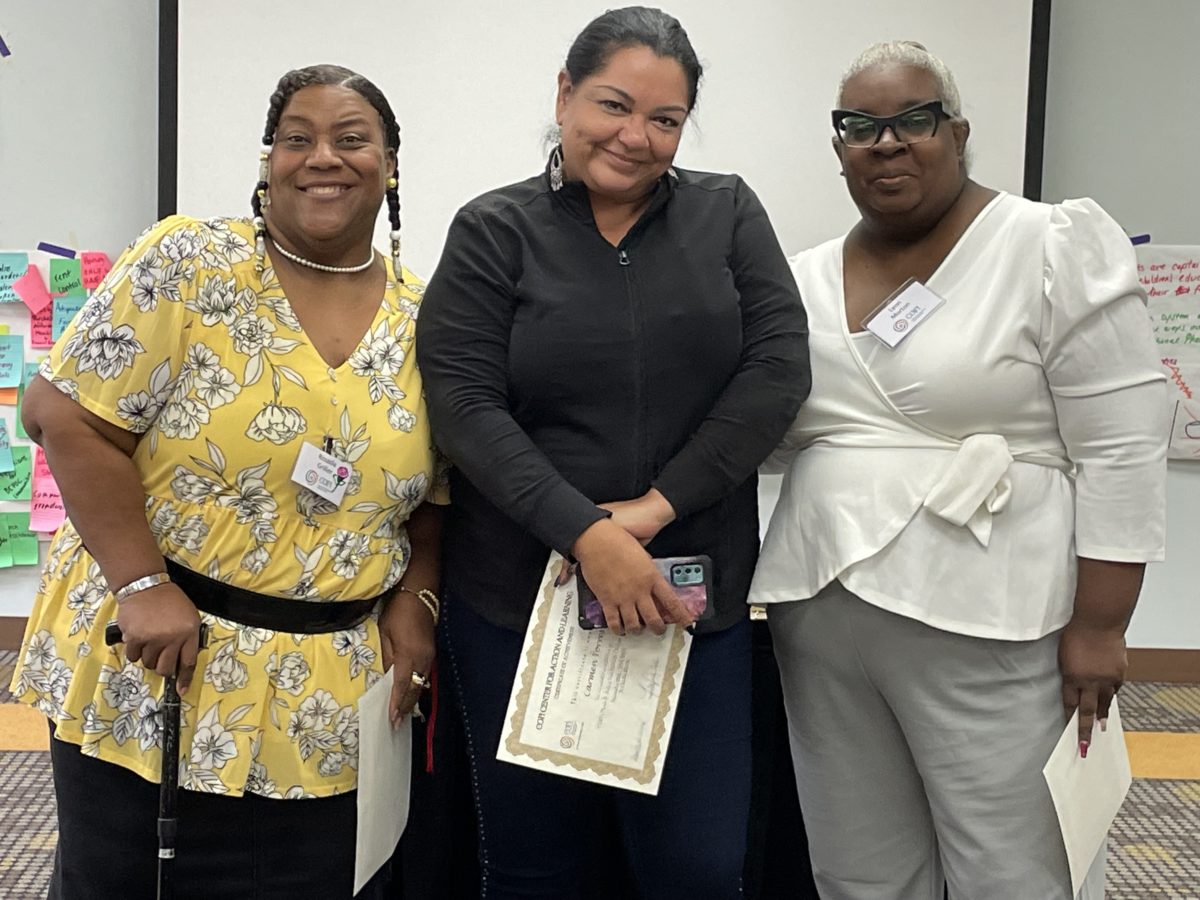 Three women stand together during Phase 3 training graduation