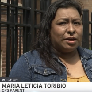 A woman speaks to a television reporter in front of her home