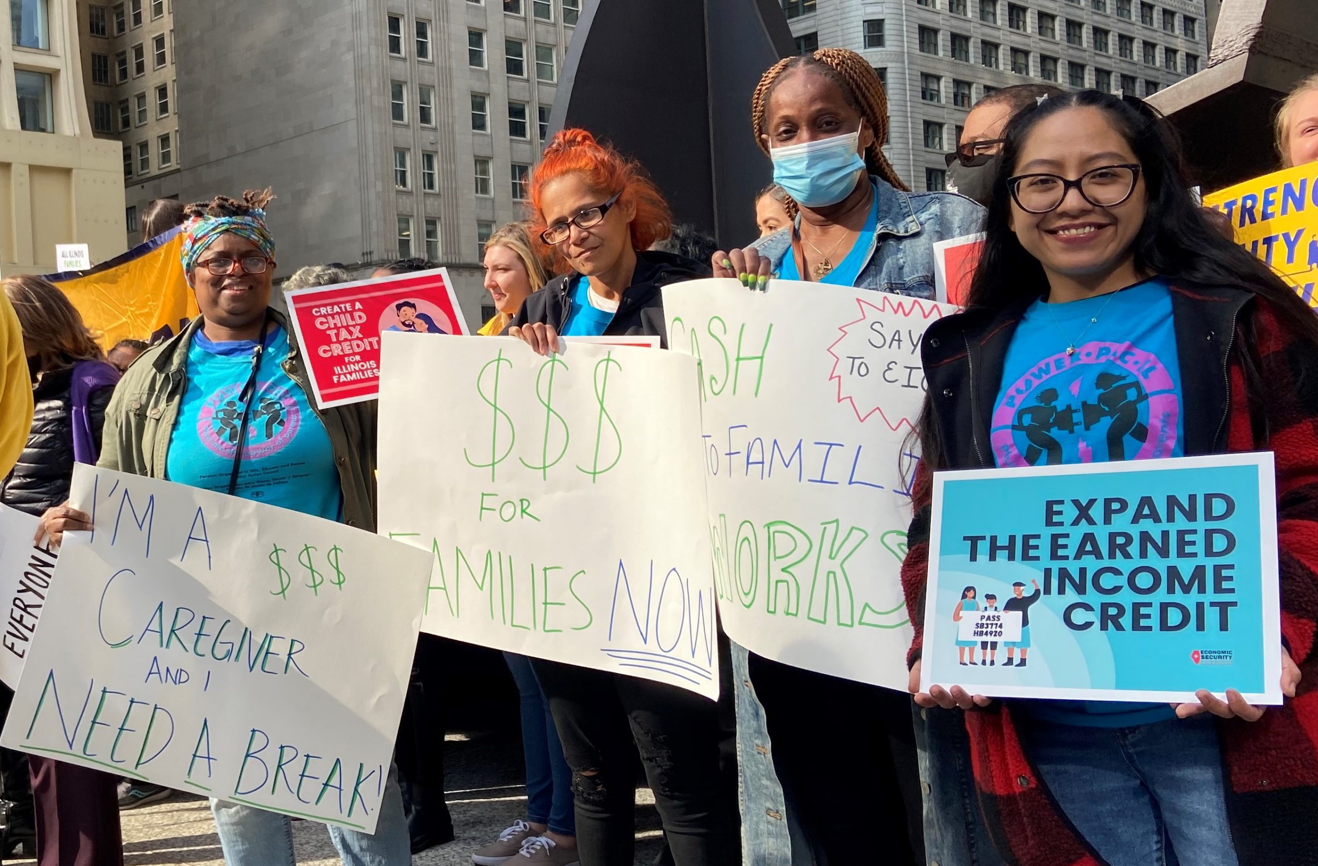 Cuatro mujeres en un mitin de desgravación fiscal sostienen carteles que abogan por la desgravación en efectivo para las familias