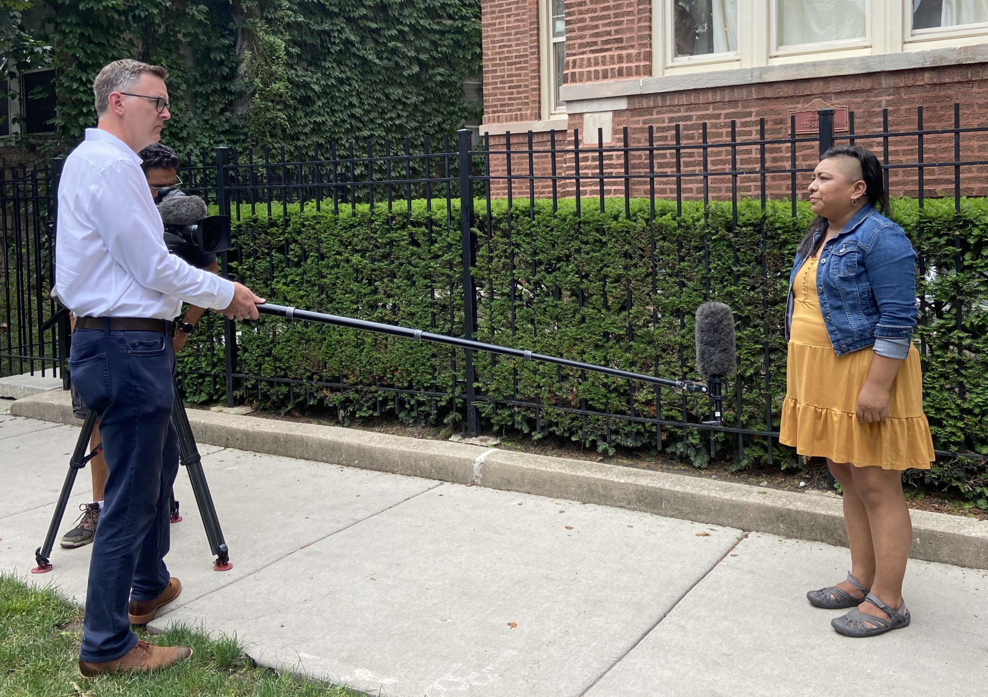 Un líder de padres es entrevistado por un reportero de televisión frente a su casa.