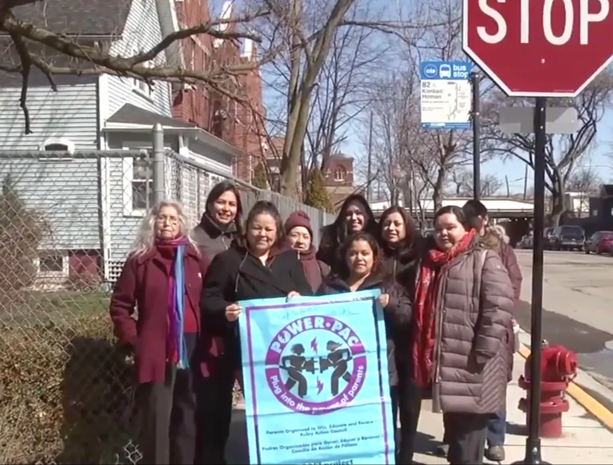 Un grupo de madres latinas se para cerca de una nueva señal de alto que ayudaron a instalar en su vecindario