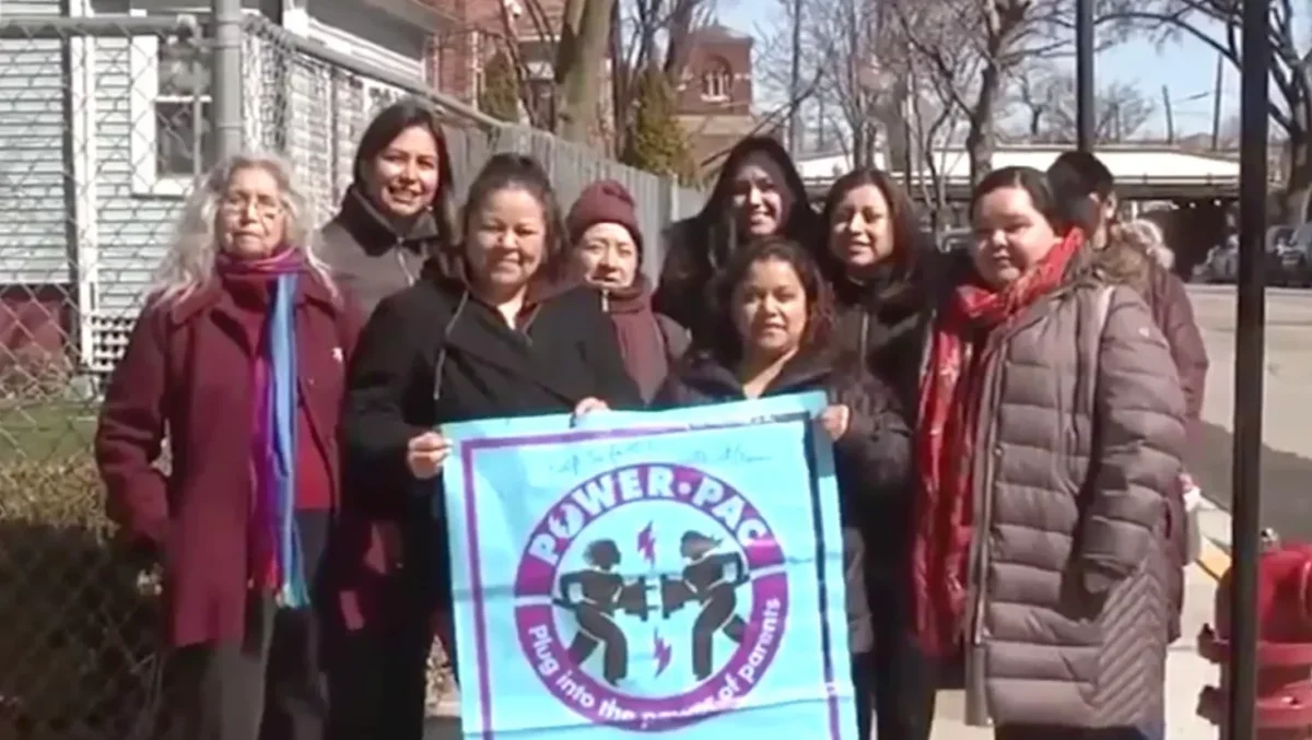 A group of Latina mothers stand near a new stop sign that they helped install in their neighborhood