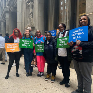 Six POWER-PAC IL parent leaders and COFI staff stand outside Chicago's City Hall with signs about lowering heating bills. Prior to this, they attended the 10.19.2023 ICC Meeting to urge the Commission to reject the rate hikes and make utilities more affordable.