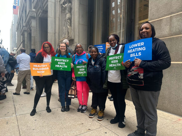 Six POWER-PAC IL parent leaders and COFI staff stand outside Chicago's City Hall with signs about lowering heating bills. Prior to this, they attended the 10.19.2023 ICC Meeting to urge the Commission to reject the rate hikes and make utilities more affordable.