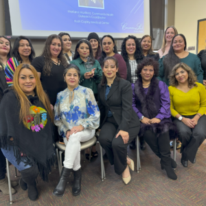 18 women, mostly Latina, are standing and sitting for a group picture