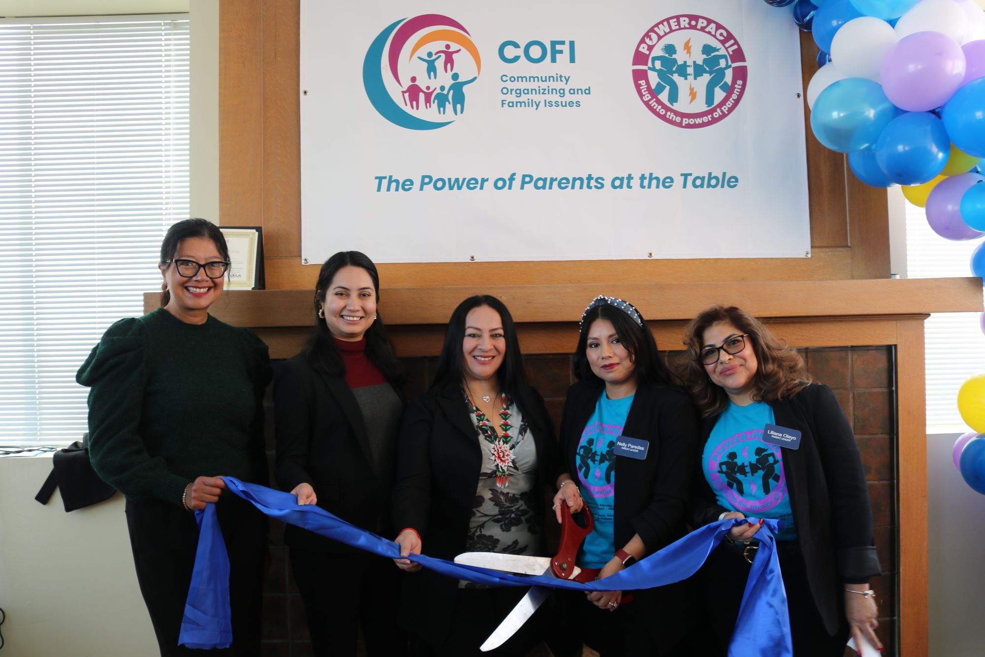 La senadora del estado de Illinois, Karina Villa, y la representante del estado de Illinois, Bárbara Hernández, se unen a los padres de COFI, Nelly y Liliana, para el corte de listón. Las mujeres sostienen una cinta azul y tijeras.