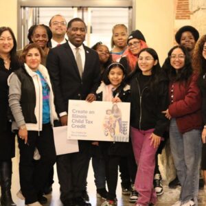 A group of about 7 Black and Latinx parents pose for a group picture with Illinois elected officials supporting a state child tax credit. The elected officials include State Representative Marcus C. Evans, Jr. (33rd District), State Senator Omar Aquino (2nd District), Rep. Mary Beth Canty (54th District), and Rep. Theresa Mah (24th District). The picture also include three children of parent leaders.