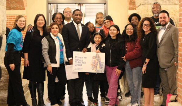 A group of about 7 Black and Latinx parents pose for a group picture with Illinois elected officials supporting a state child tax credit. The elected officials include State Representative Marcus C. Evans, Jr. (33rd District), State Senator Omar Aquino (2nd District), Rep. Mary Beth Canty (54th District), and Rep. Theresa Mah (24th District). The picture also include three children of parent leaders.