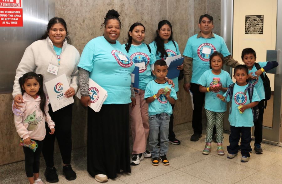 A group of about 5 adults and 5 children stand and pose for a group photo