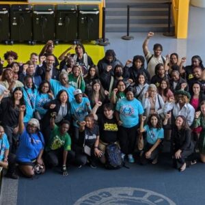 A large group picture of students, parents, and CPS staff with their fists in the air