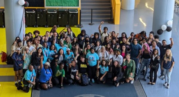 Una foto grupal grande de estudiantes, padres, personal de CPS y miembros de la comunidad celebrando la ampliación de la política de seguridad escolar. Muchas personas tienen los puños en alto