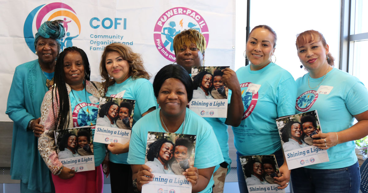 4 Black women and three Latina women pose for a group picture with "Shining a Light" booklets