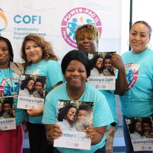 Four Black women and three Latina women stand for a group picture. Six are holding COFI's "Shining a Light" publication