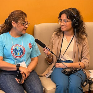 Lili talking to a radio journalist who is wearing headphones and is holding a microphone pointed at Lili