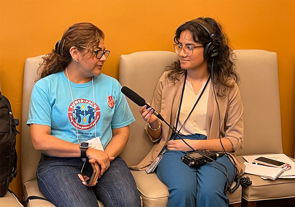 Lili hablando con un periodista de radio que usa audífonos y sostiene un micrófono apuntando a Lili