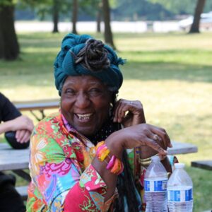 Picture of an older, smiling black woman in a park setting.