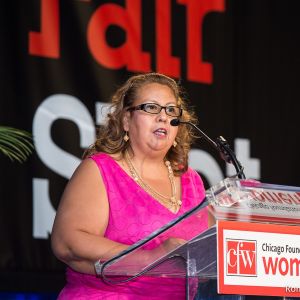 A Latina woman speaking at a podium